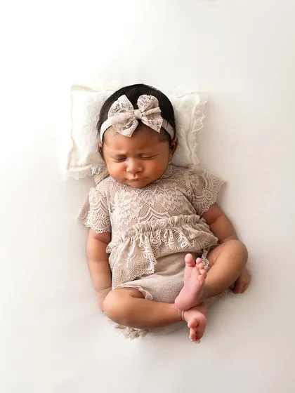 A full-body shot of the baby in her lace outfit. This pose is great for showing just how tiny and curled-up newborns are.