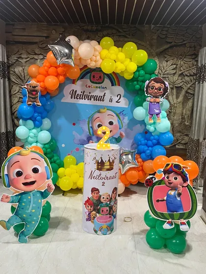 A vibrant Cocomelon theme for a 2nd birthday, featuring a rainbow balloon arch and cutouts of all the favorite characters.
