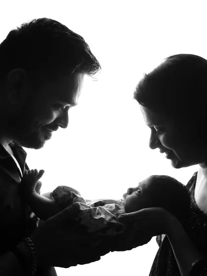 This is one of the most precious moments, a new beginning for a family. This silhouette shot captures the quiet love and wonder as new parents hold their baby for the first time. It's a simple, powerful memory of when three became one.