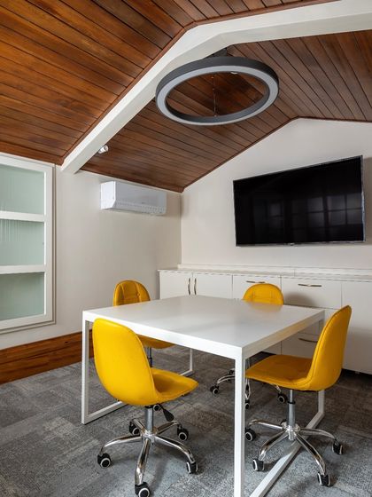 A dedicated meeting room carved out within the attic, complete with modern technology and furniture, showing how we blend new needs with old structures.