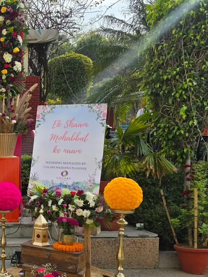 Another angle of the 'Ek Shaam Mohabbat ke naam' welcome sign, showing how it's integrated into the overall entrance decor with large marigold spheres and rustic wooden crates.