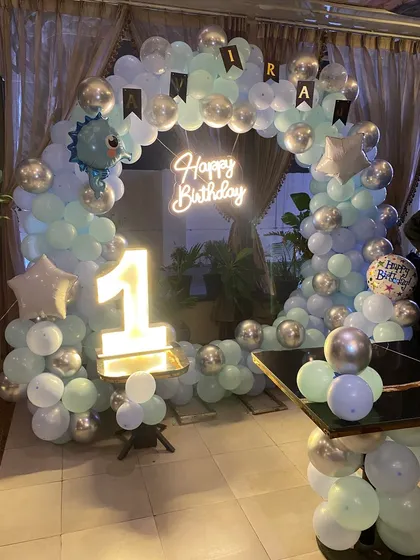 A clear shot of the dinosaur-themed first birthday ring decoration with a 'Happy Birthday' neon sign.