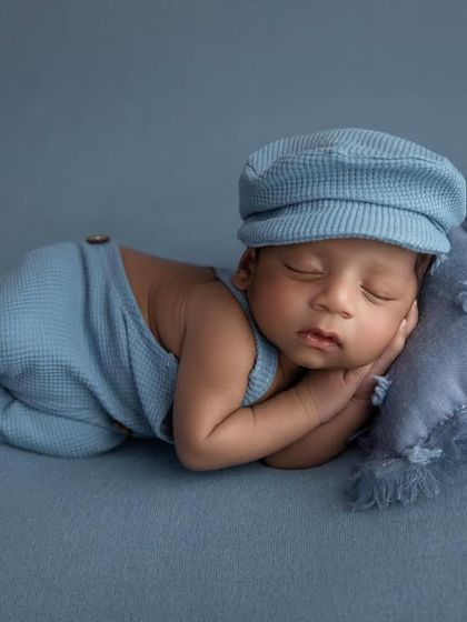 A matching blue knit hat completes this adorable outfit for a classic newborn boy portrait.