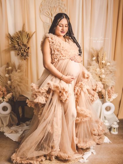 A full-length standing view of the Paige gown. The slit in the front allows for a peek of the baby bump, adding a sweet touch to this dramatic look.