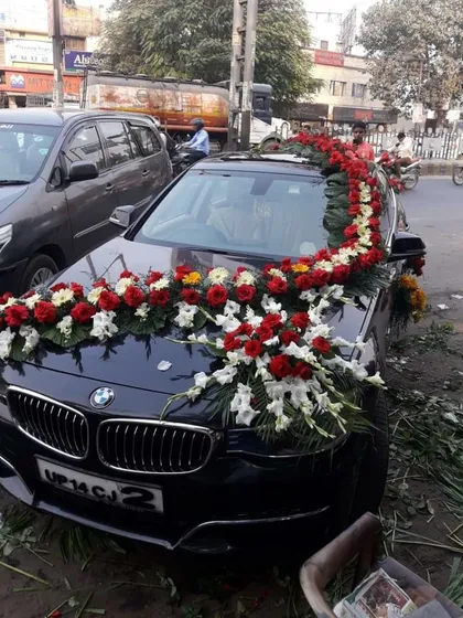 A premium BMW decorated with a garland of red and white flowers. I provide on-location service to decorate any car model, ensuring a royal look for the groom's arrival.