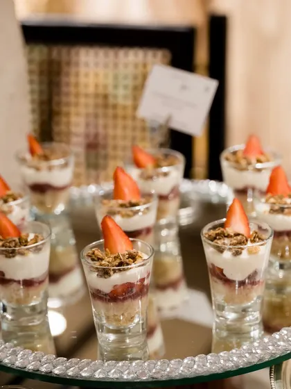 Strawberry and granola parfaits served in shot glasses. This is a light and elegant dessert option, perfect for brunches or as a refreshing end to a meal.
