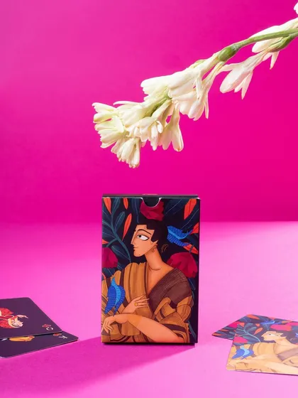 An artistic shot of a Namostutay card box against a bright pink background, with a fresh flower. This creative composition is modern and highly shareable on social media.