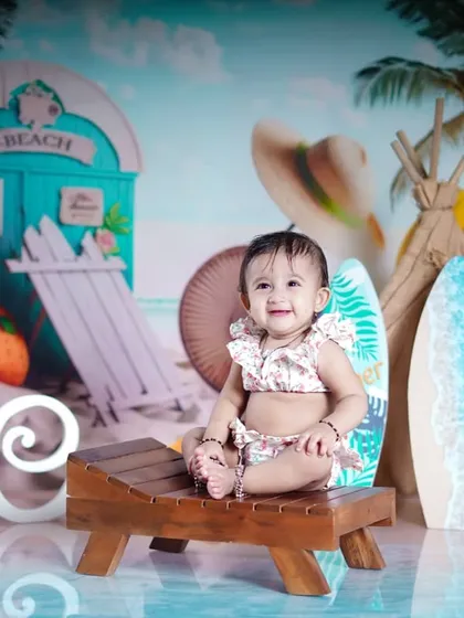 A day at the beach. This little girl is ready for some sun and surf in our beach-themed studio setup, complete with a beach hut and surfboards.