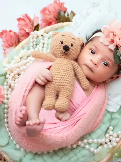 A sweet newborn holding a teddy bear, showcasing their tiny grip. I use props like these to add a touch of tenderness to the photos.
