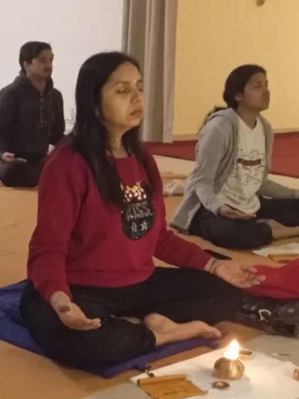 A close-up of a participant meditating with her ghee lamp, deeply involved in the process of elemental cleansing.