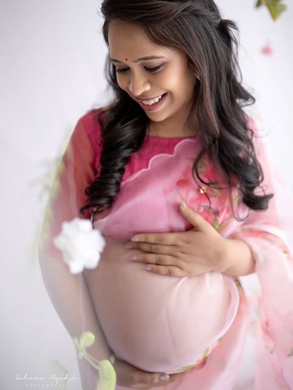 A close-up shot focusing on the beautiful baby bump, draped in a sheer floral organza saree. It's a tender and intimate portrait of the connection between mother and child.