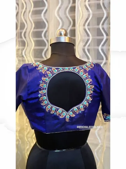 A royal blue silk blouse featuring a circular back opening. The border is meticulously handcrafted with zardosi and paisley motifs, showcasing fine craftsmanship.