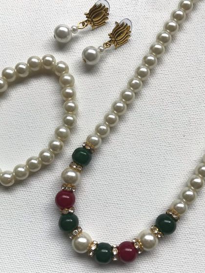 This classic pearl set includes a necklace, bracelet, and earrings, with red and green beads for a traditional touch. It's a beautiful choice for ethnic wear and is available in adult and kid sizes.