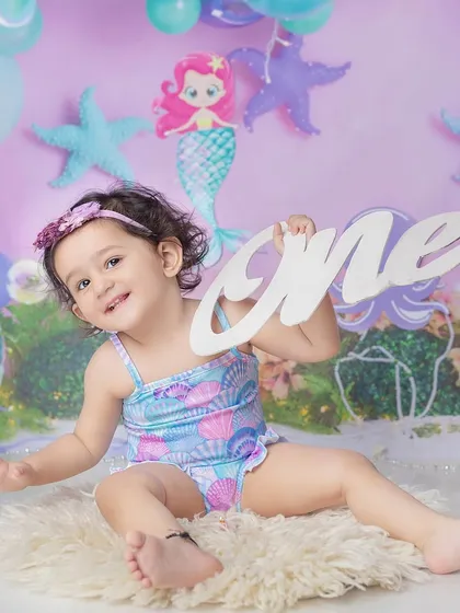 A happy little mermaid celebrating her first birthday. The 'one' sign adds that special milestone touch to the themed shoot.