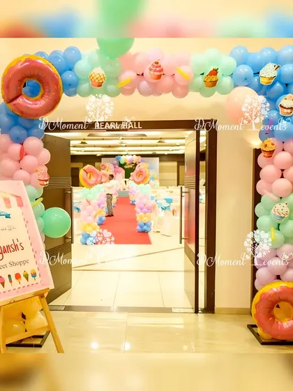 A delightful entrance to "Aayansh's Sweet Shoppe." The balloon arch is decorated with pastel colors and donut-shaped foil balloons, perfectly setting the tone for a Candyland-themed birthday party.