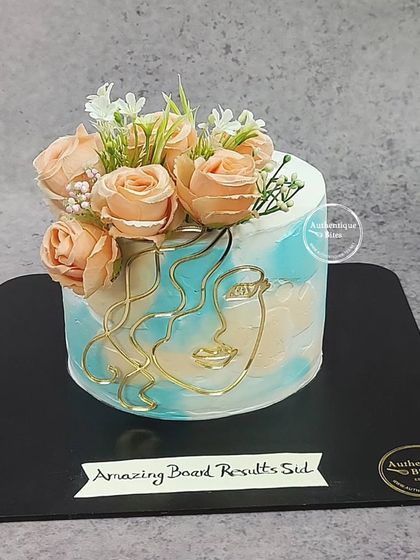A butterscotch floral beauty. This cake features a modern abstract face design, topped with a bouquet of peach-colored roses.
