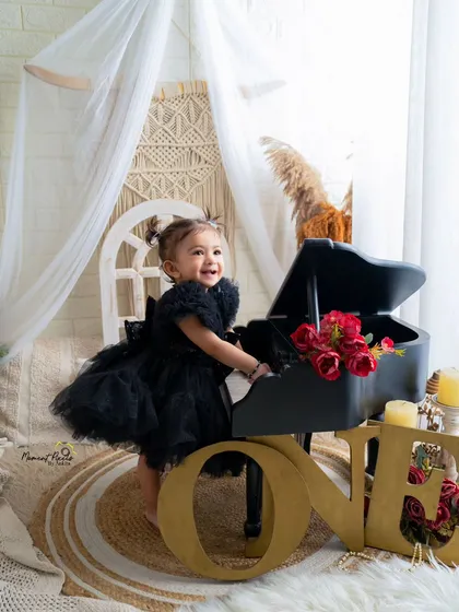 A little musician celebrating her first birthday. Her joyful smile lights up this beautiful bohemian-themed setup with a miniature piano and the number 'One'.