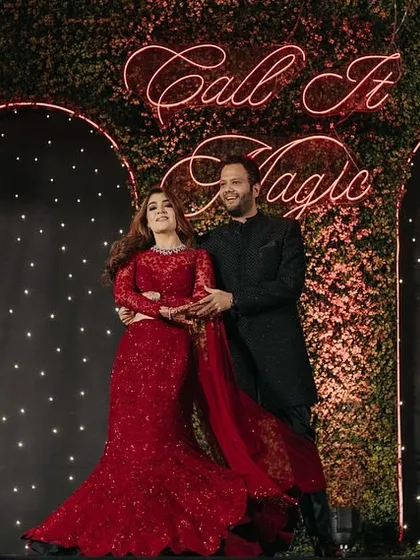 A "Call It Magic" neon sign against a backdrop of twinkling lights and foliage, creating the perfect stage for the couple's performance.