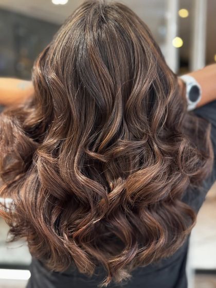 Another view of the mocha hair color balayage, showing how the curls enhance the color's depth and movement.