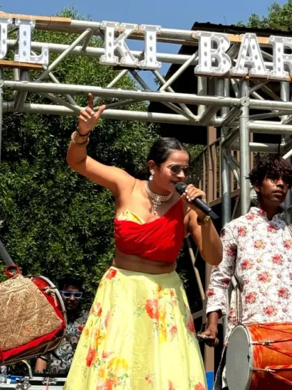 Leading the baraat procession with the dhol players, microphone in hand, ensuring the energy never drops.