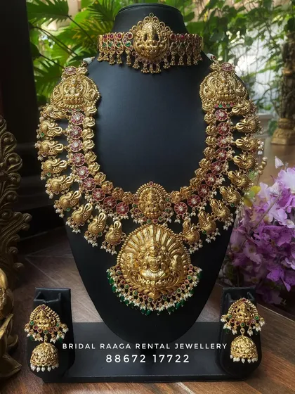 A beautiful temple jewellery set with a large, ornate pendant. The choker and haram both feature intricate carvings and are perfect for a traditional bridal look.