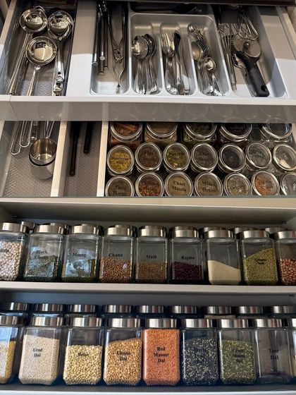 A multi-level view of a fully organized drawer system, showcasing cutlery, spices, and decanted grains all stored with precision and care.