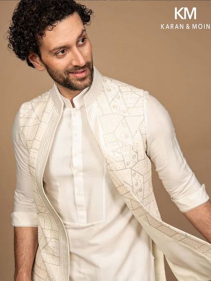 This ivory kurta and Nehru jacket ensemble features a unique geometric embroidery, blending Indian craftsmanship with modern minimalism. It creates a look that’s timeless yet effortlessly contemporary, for the man who believes sophistication lies in the details.