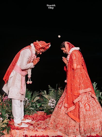 The couple bows in a traditional gesture of respect during their Varmala ceremony, a moment of reverence and unity.