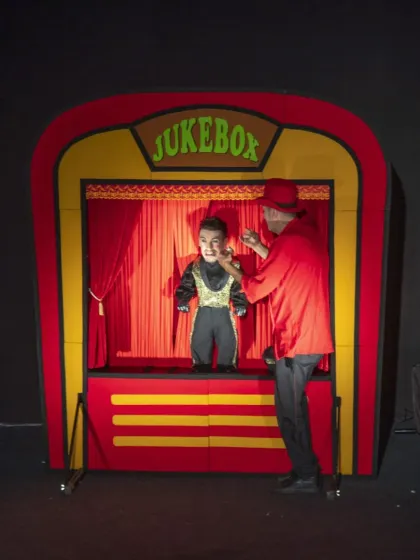 The puppeteer of 'Jukebox' adjusts the costume of one of his charismatic puppets, showing the care and attention to detail that goes into each performance.
