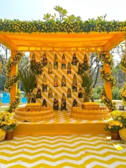 A classic Haldi ceremony setup, featuring a mandap draped in yellow and adorned with fresh flowers. The chevron-patterned floor and traditional seating create a perfect blend of modern design and timeless tradition.