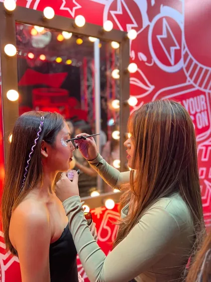 Another shot of my glitter bar setup, showing an artist applying a detailed look to a client in front of the vanity.