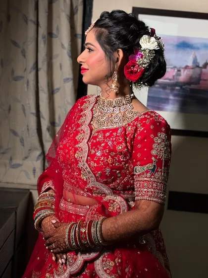 A side view of the bride, showing her complete look with the floral bun, elegant jewelry, and flawless makeup.