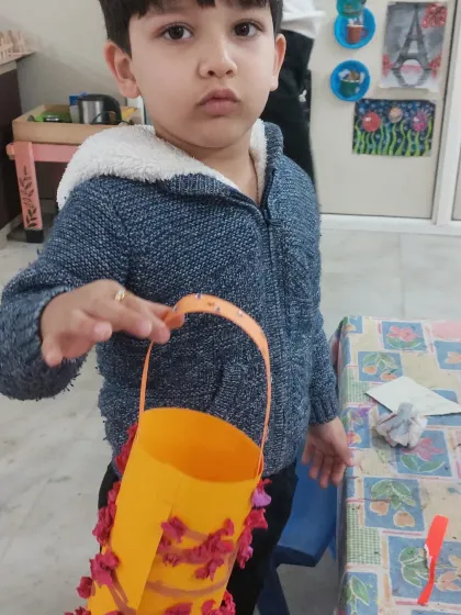 This little one is so proud of the paper lantern he created. Crafting helps build fine motor skills and a sense of accomplishment.