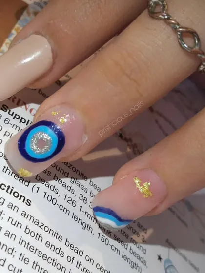 A close-up of this evil eye nail art. I combined the protective symbol with gold leaf and abstract blue waves for a modern, chic design.