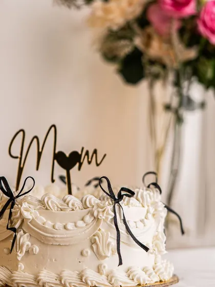 A beautiful white vintage cake I made for a special mom. The delicate piping and simple black ribbon bows give it a timeless, elegant feel.