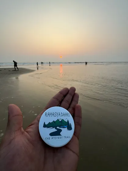 Holding up the Rahasya Daari badge against a beautiful beach sunset in Gokarna.