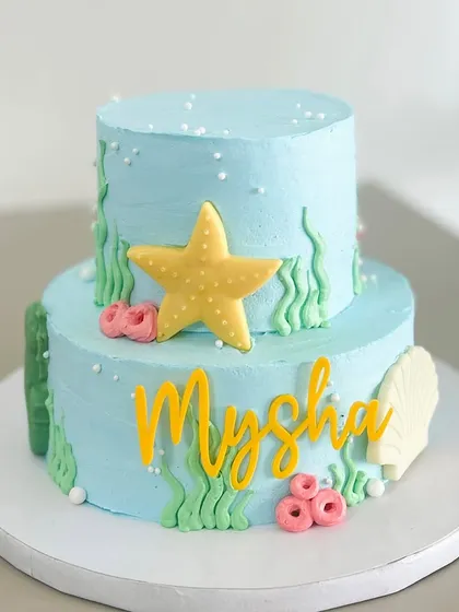 An underwater adventure awaits. This two-tier cake is decorated with hand-crafted chocolate shells, starfish, and seaweed, creating a magical ocean scene for Mysha's birthday.