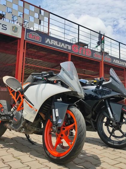 Two track-prepped KTM RC 390s parked in front of our garage. Many riders in our community are passionate about modifying their bikes for optimal track performance.