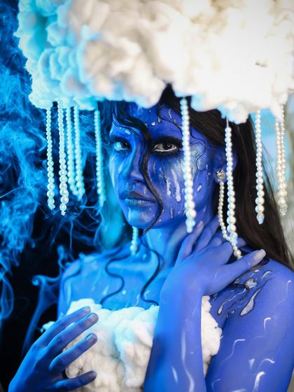 An ethereal fantasy look inspired by clouds and rain, using blue body paint and a custom cloud headpiece.