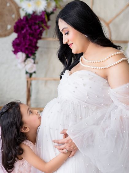 A kiss for the baby bump from the big sister. It’s a heartwarming image that captures the growing love in the family.