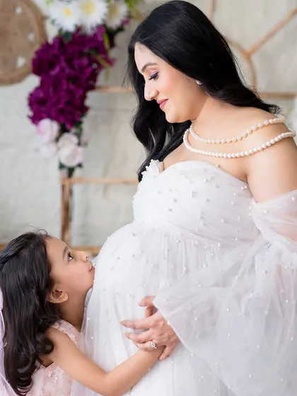 A kiss for the baby bump from the big sister. It’s a heartwarming image that captures the growing love in the family.