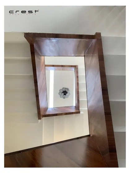 A view looking up the staircase of the 'Framed House.' The continuous spiral is lined with polished wood, creating a warm, twirling vortex of texture and form that draws the eye upward.