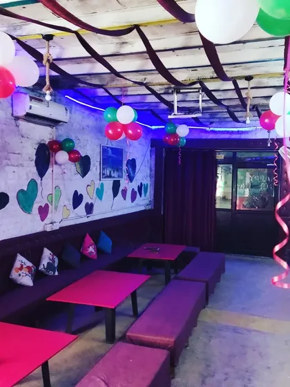 This image shows how I can decorate an indoor cafe space for a party using simple balloon bunches and streamers on the ceiling to add color and fun.