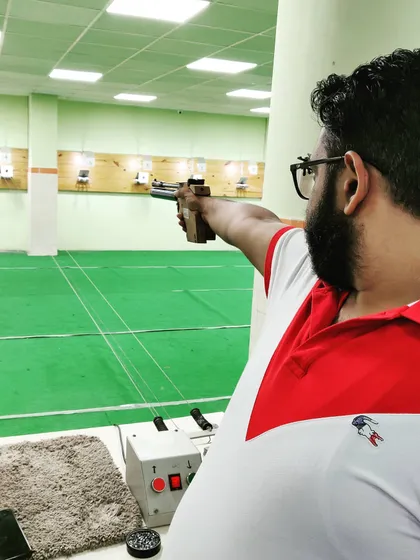 A close-up of a pistol shooter aiming down the range. Practice makes you perfect.