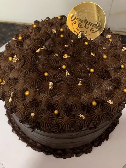 A rich chocolate cake covered in chocolate frosting and sprinkled with gold dust.