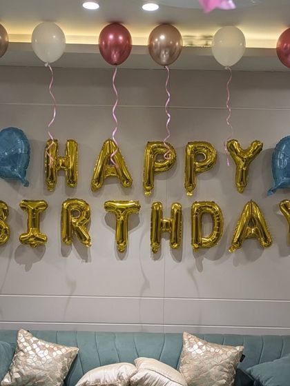 A close-up of the "Happy Birthday" foil balloon banner, a classic and essential part of any birthday room decoration.