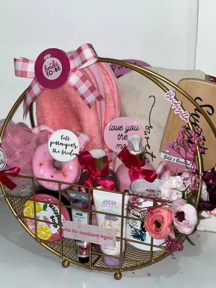 A golden basket filled with pampering goodies for the bride-to-be. Featuring a donut-themed bath bomb, whipped soap, and other skincare treats, it's the perfect way to say "let the countdown begin".