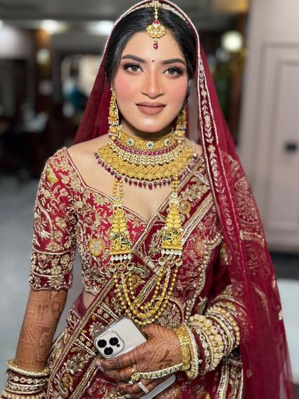 A beautiful South Indian inspired bridal look. The makeup features defined eyes and a warm-toned base to complement the heavy gold jewellery and traditional red saree.