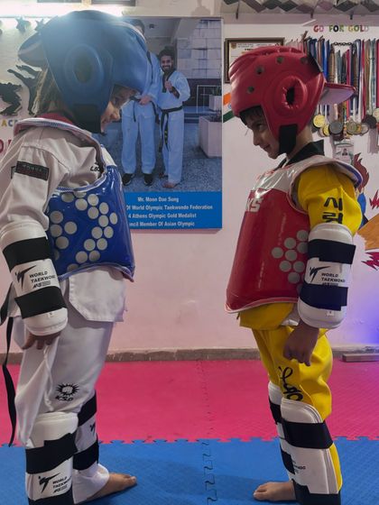 The calm before the storm. Two of our young fighters, fully geared up, face each other with intense focus before their sparring match begins.