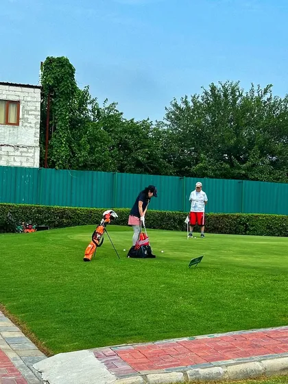 A young golfer gets a lesson on the putting green, learning the fundamentals of the short game.